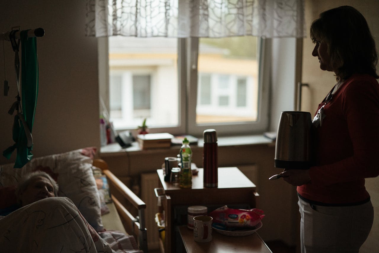 gallery-6 A caregiver prepares a warm drink for a senior in a peaceful retirement home setting.