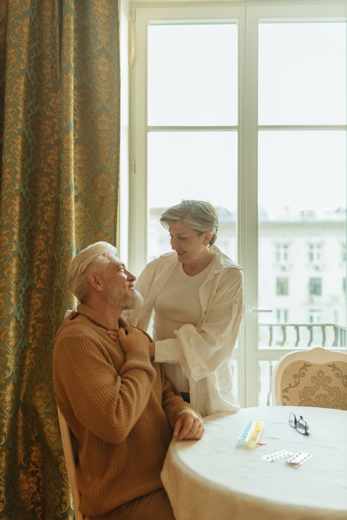 services-01 Warm and affectionate scene of an elderly couple sharing a moment at home by a window.